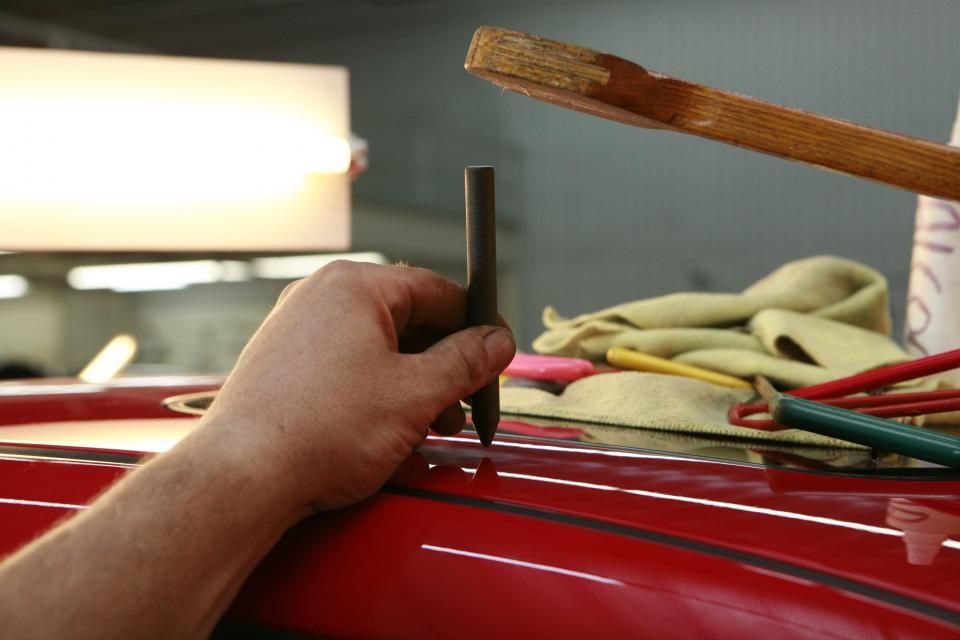Reprise d'un enfoncement sur la tôle d'une carrosserie rouge